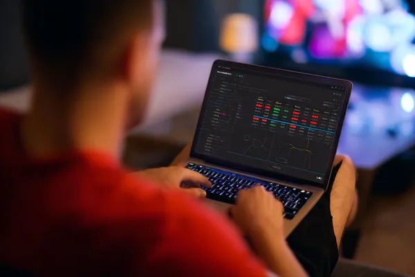 A man focused on his laptop with live stats in the background, highlighting the dedicated sports and gaming features of the TAS71 mobile app.