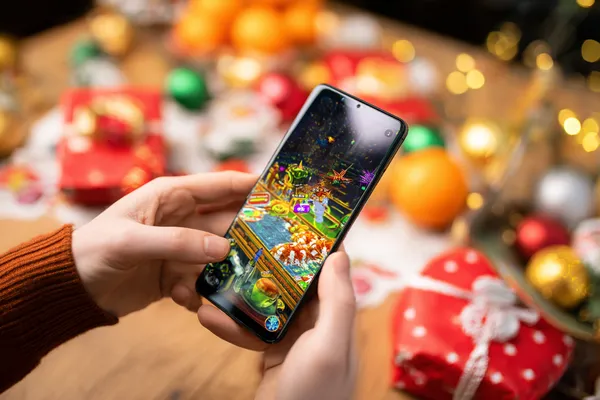A player using their smartphone during a festive local event, representing TAS71’s fully mobile-friendly casino.